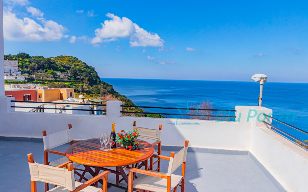 Terrazza panoramica vista mare dell'appartamento Mediterraneo a Ponza, arredata con tavolo e sedie in legno, ideale per rilassarsi e cenare all'aperto